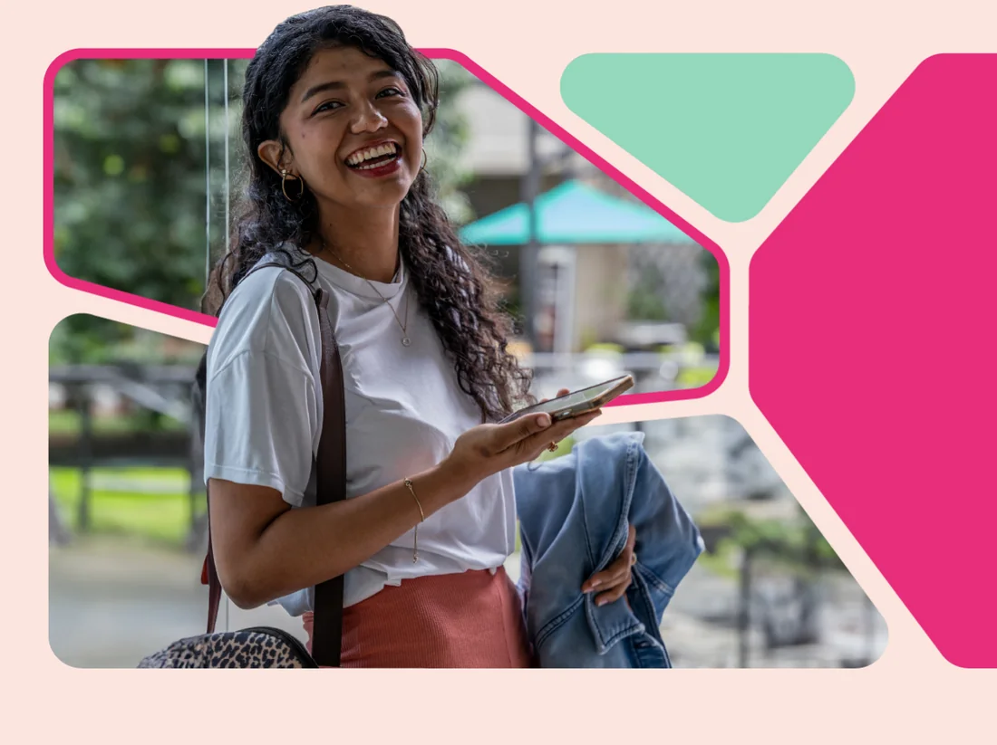 Estudiante de Cesde sonriendo mientras usa su celular en el campus